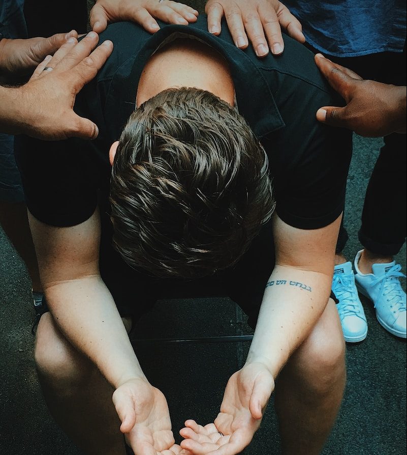 man sitting on chair holding and surrounded by people